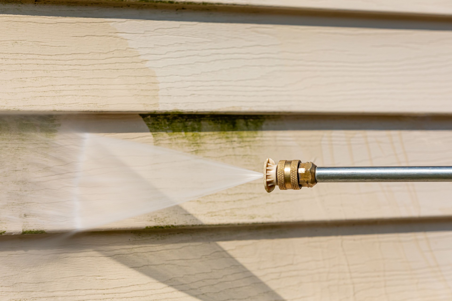 Cleaning algae, mold and mildew from vinyl siding of house with pressure washer. Home repair, maintenance and exterior cleaning concept.